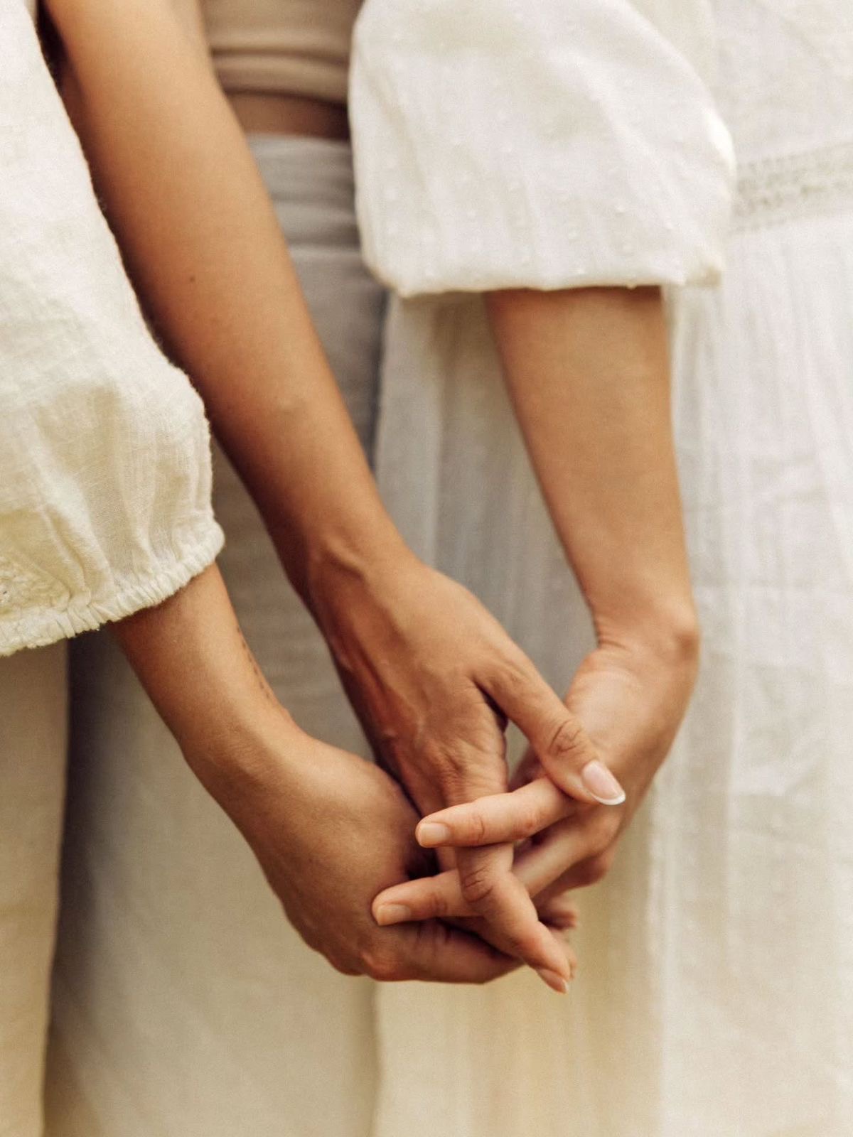 Two women holding hands gently
